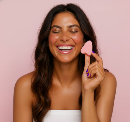 Woman holding a FemmeFlo menstrual sponge against a pink background