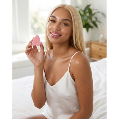 Woman holding a FemmeFlo menstrual sponge while sitting on a bed